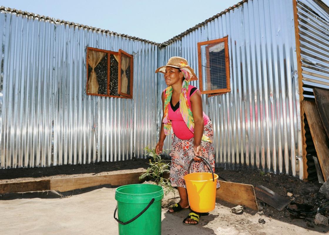 Kvinne henter vann til hjemmet sitt i Klipheuwel i Sør-Afrika 