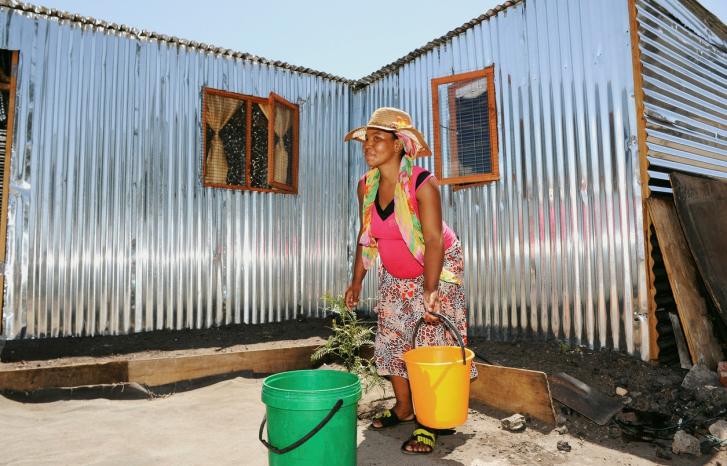 Kvinne henter vann til hjemmet sitt i Klipheuwel i Sør-Afrika 