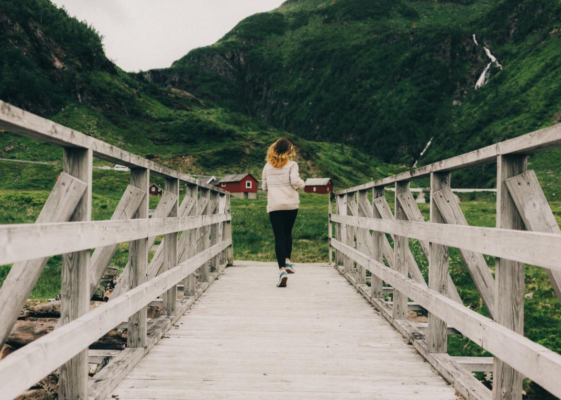 Kvinne går over bro på fjellet