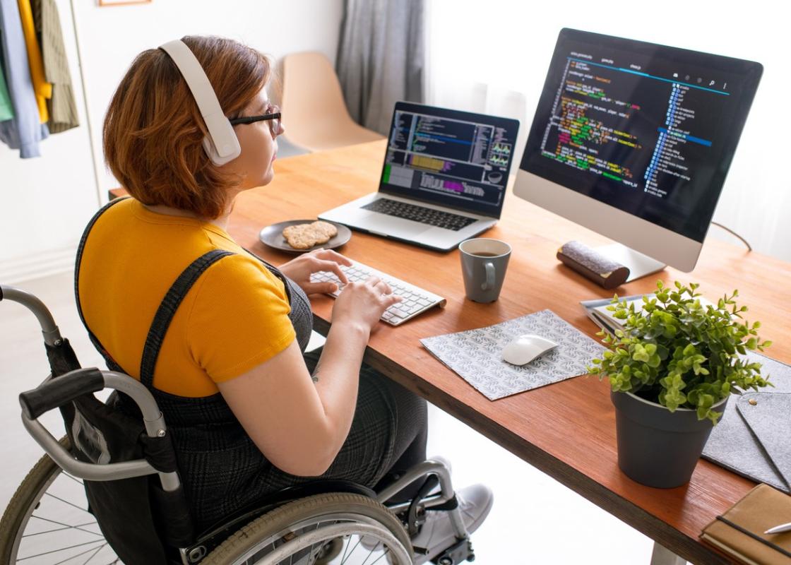 Ung kvinne i rullestol foran dataskjerm